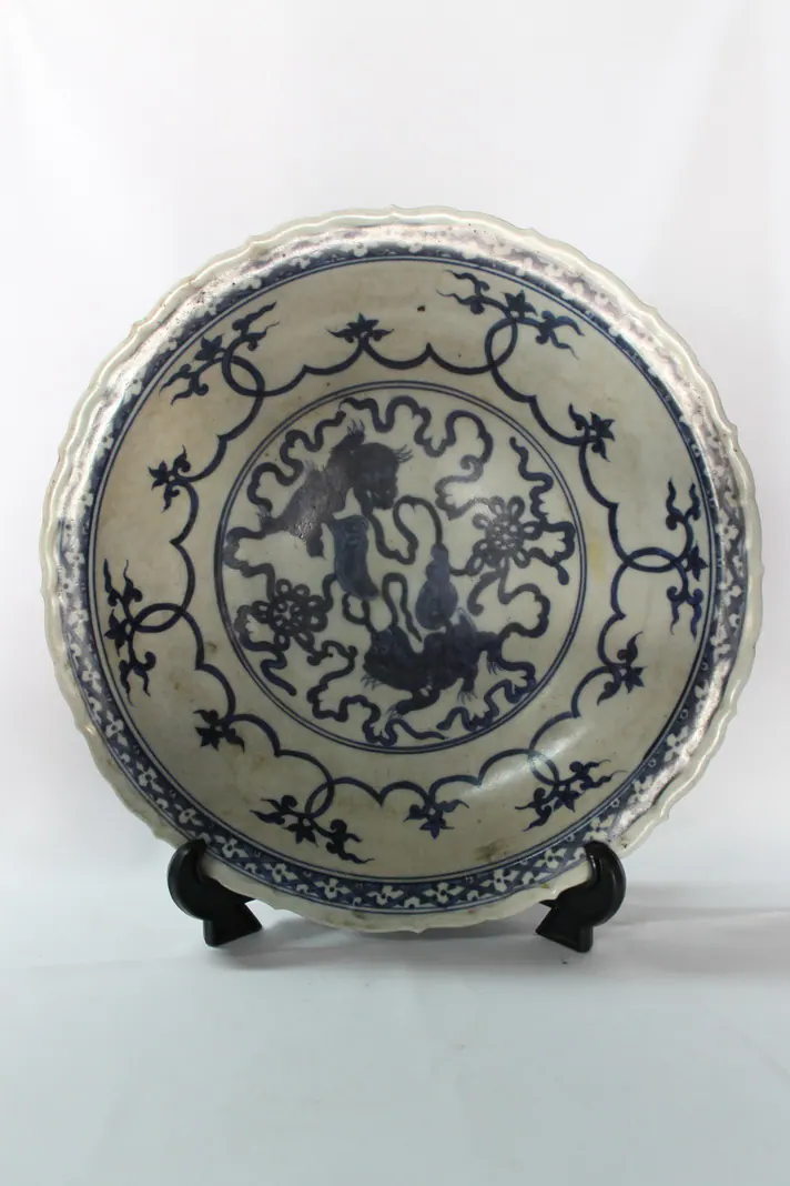 Blue and white dish on a stand with a barbed rim, showing two lions with ribboned balls in the centre