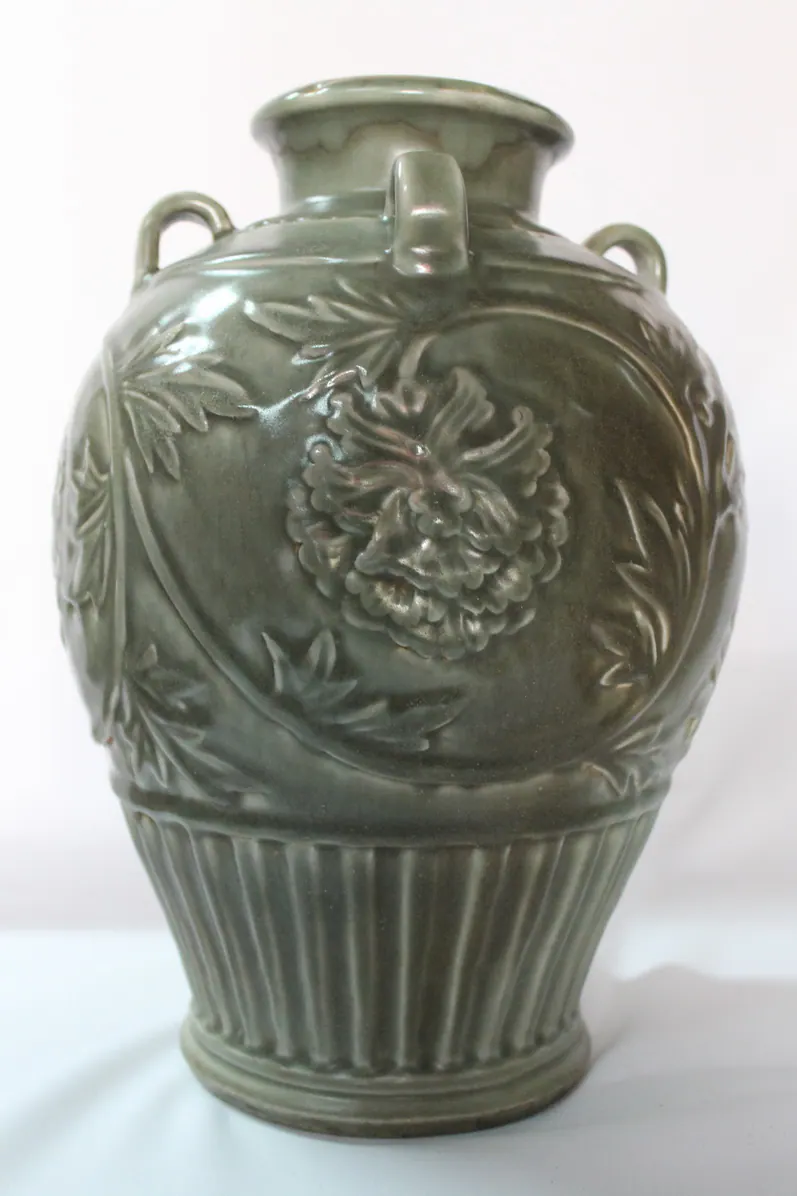 Celadon glazed vase with a carved peony medallion and two loop handles, front view