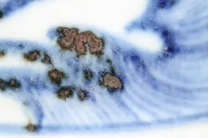 Close-up of blue and white painting with dark iron spots where the cobalt gathered
