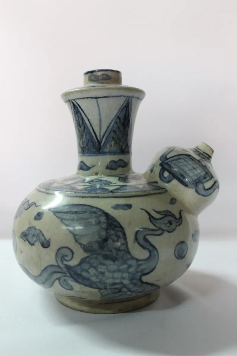 Blue and white kendi with a winged phoenix across the body and the spout to the right