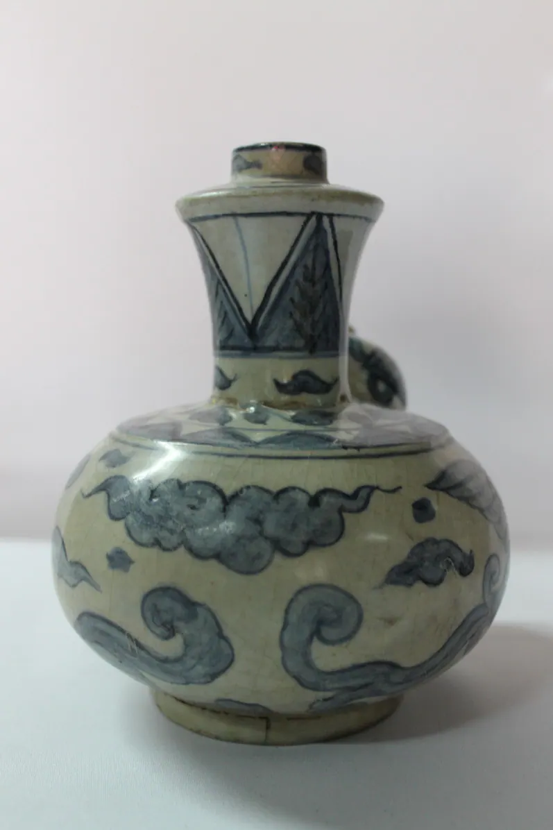 Reverse of a blue and white kendi showing scrolling clouds, with the spout just visible behind