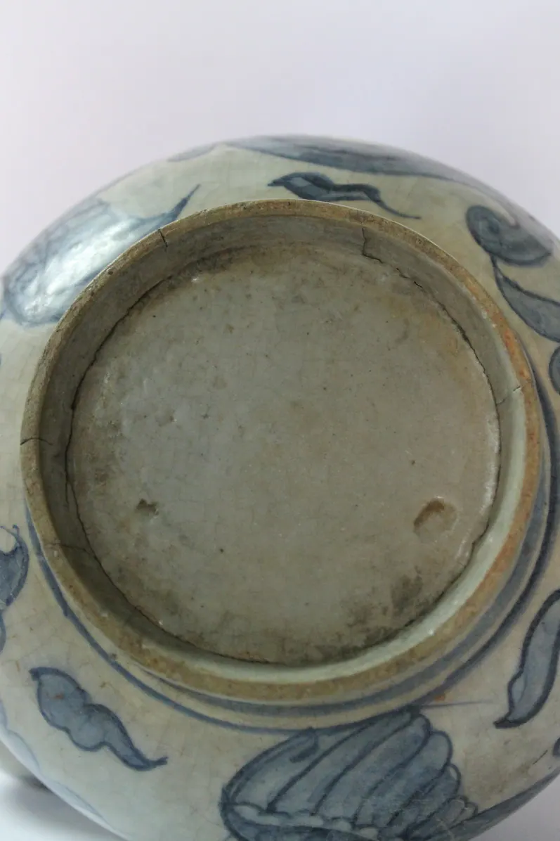 Close-up of the kendi's footring showing the exposed clay body and crackled glaze