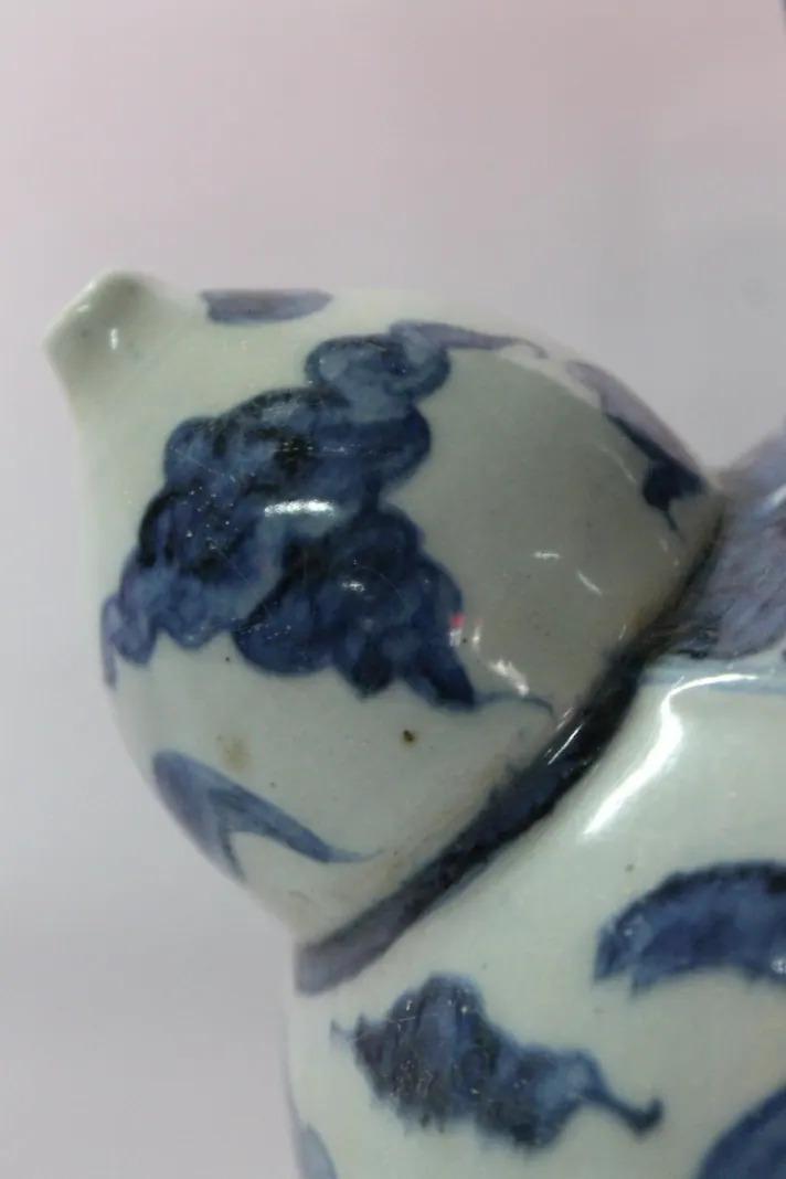 Close-up of the kendi's spout opening on the shoulder amid cloud scroll decoration