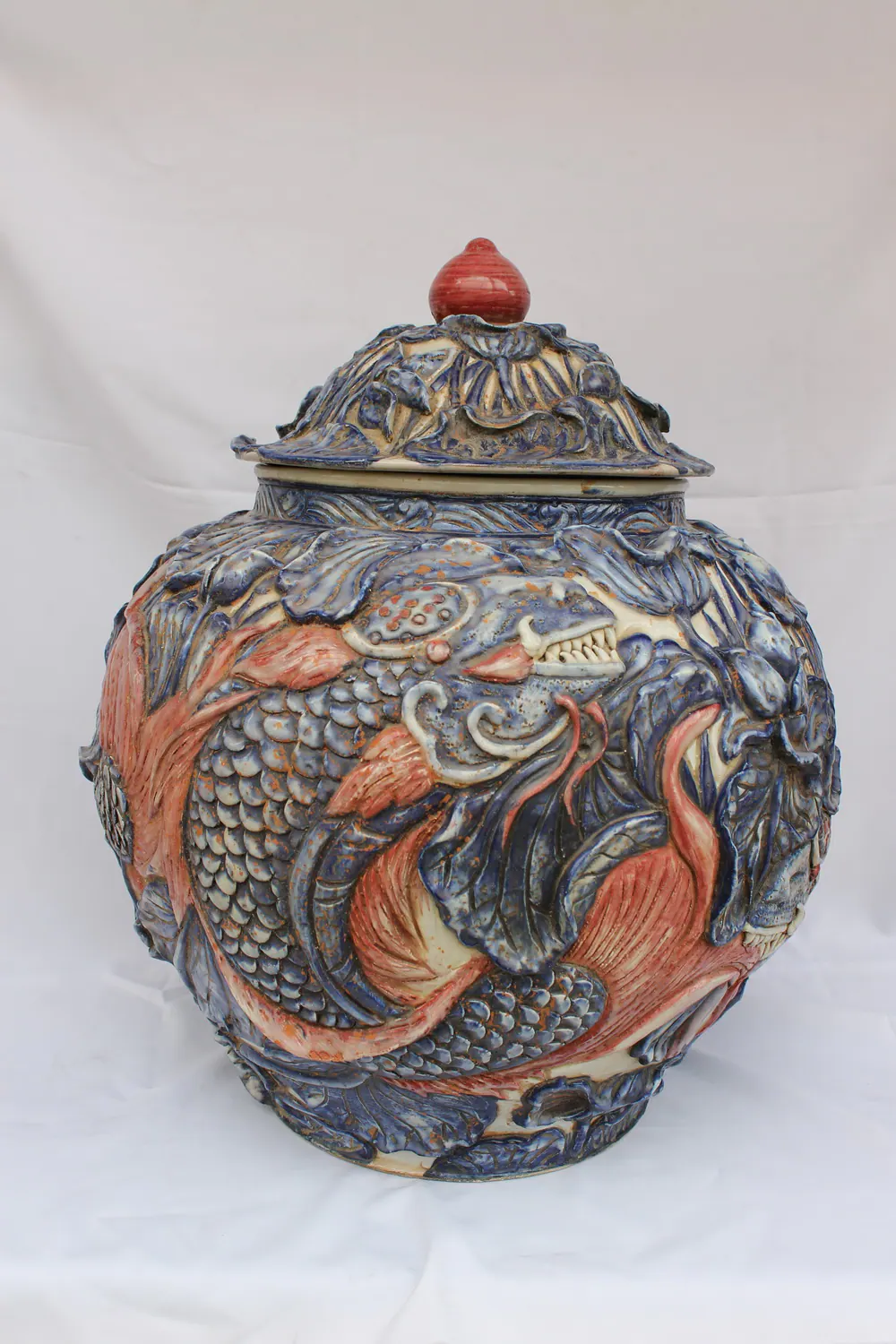 Three-colour relief porcelain jar with lid, front view, showing a large carp in high relief