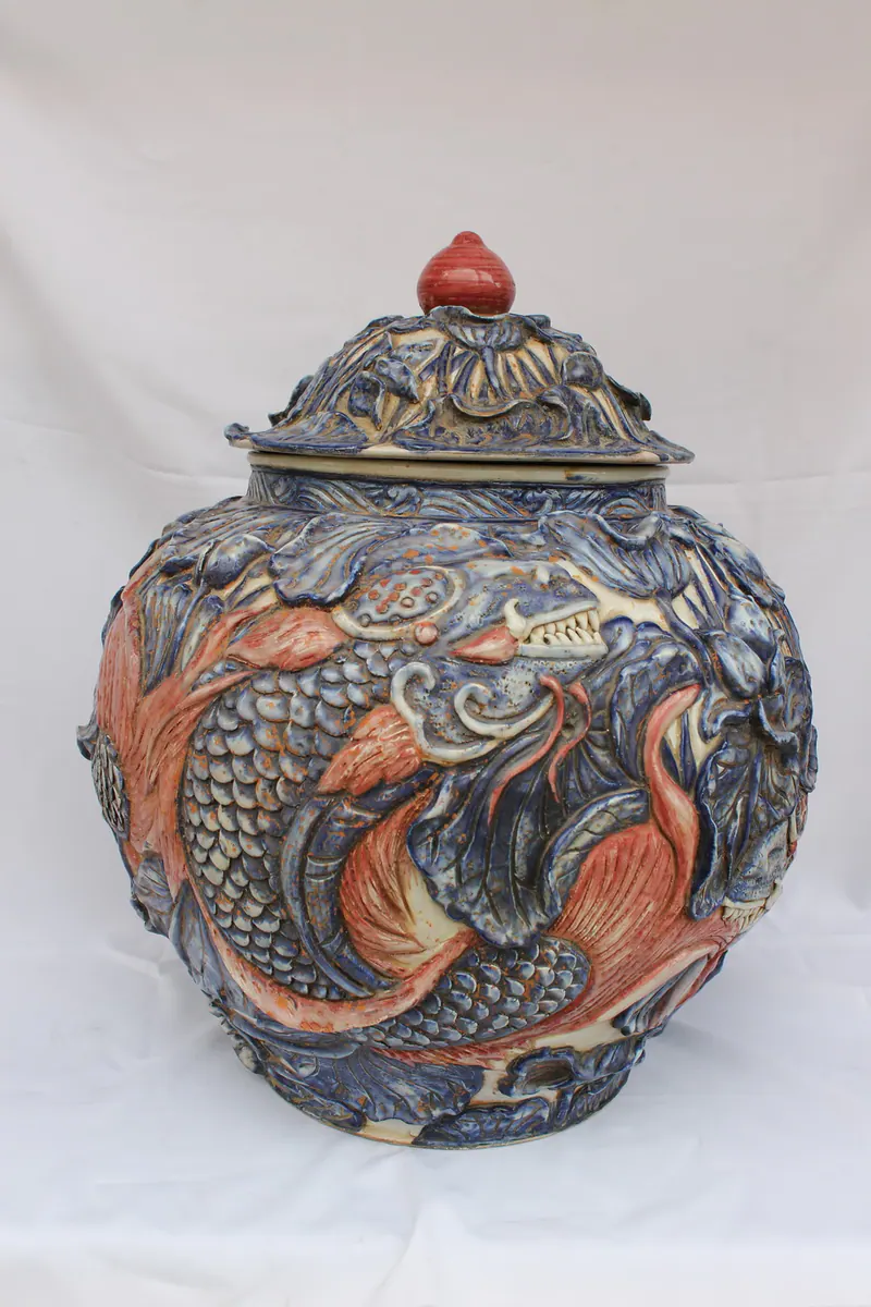 Three-colour relief porcelain jar with lid, front view, showing a large carp in high relief