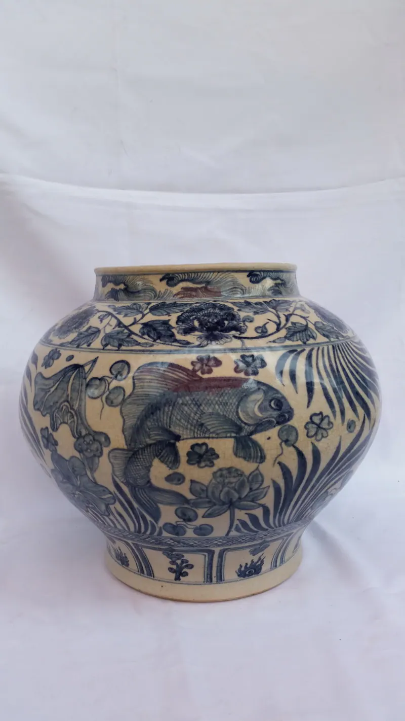 Front view of the jar showing a large carp swimming among lotus leaves and aquatic plants