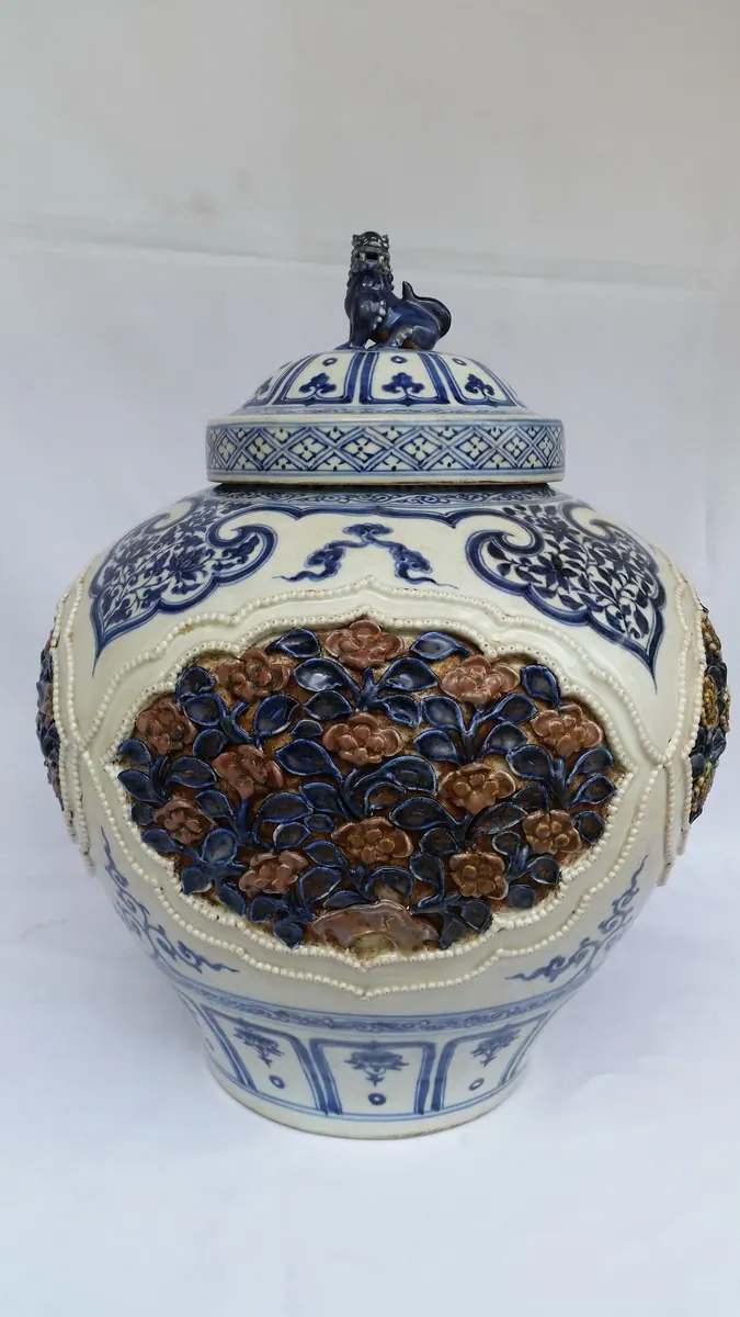 Front view of the lidded jar with a lion-form finial and blue and copper-red floret medallions around the body