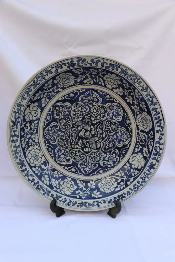 Front view of the blue and white plate on a wooden stand, full painted surface visible
