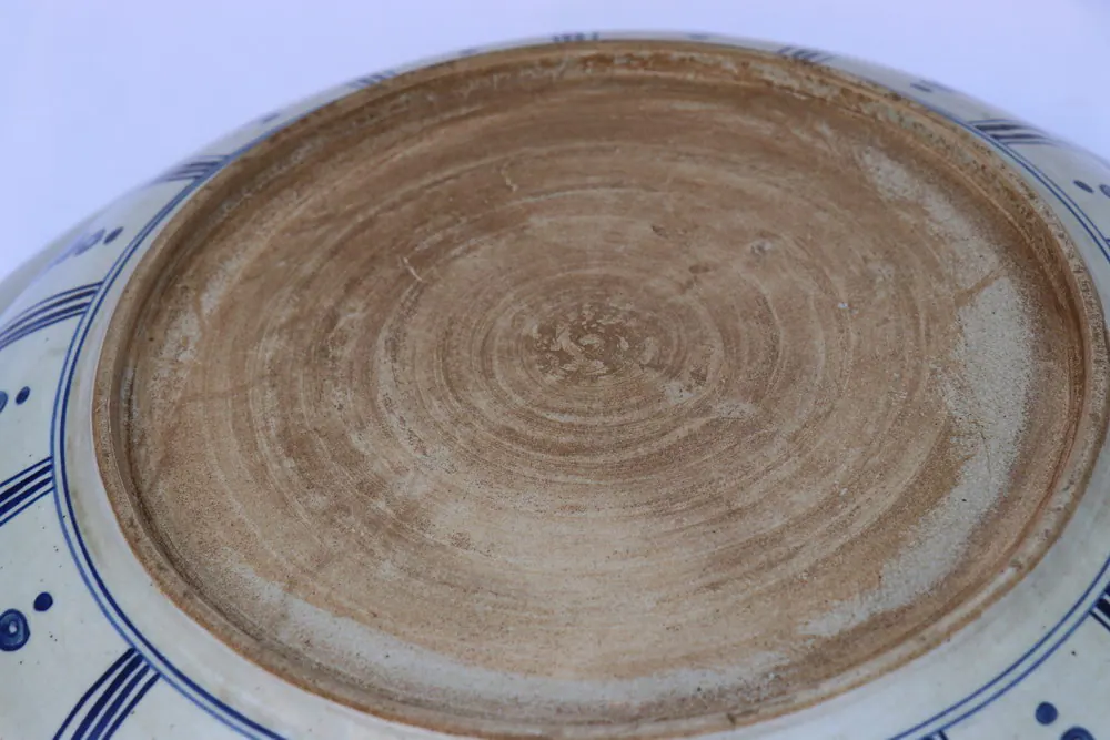 Underside of the plate with the sandy unglazed base and blue foliate panels around the footring
