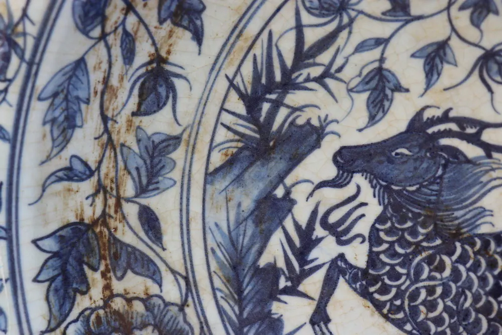 Close-up of a qilin figure amid bamboo and foliage, painted in underglaze blue within a roundel