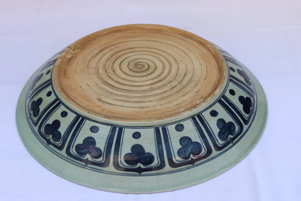 Overhead view of the plate's unglazed base, spiral throwing marks encircled by a trefoil border