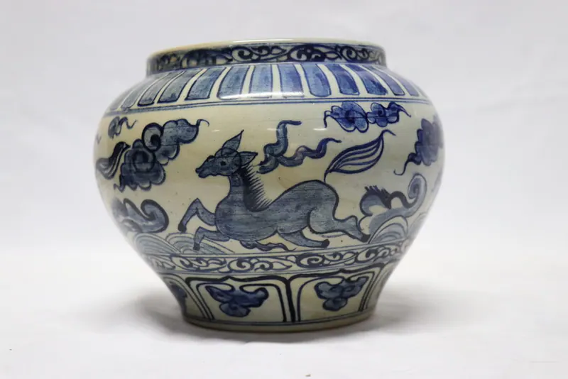 Front view of the blue and white pot with a running deer amid clouds above a wave band