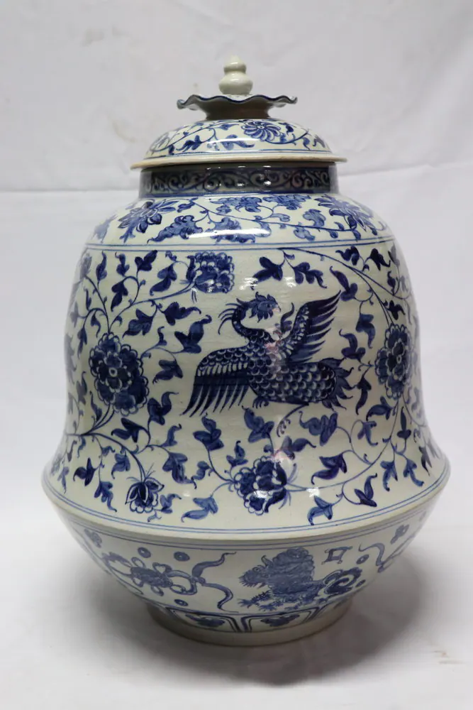 Front view of the covered jar on a white backdrop, showing a phoenix above peony scrolls and a foo dog frieze at the foot