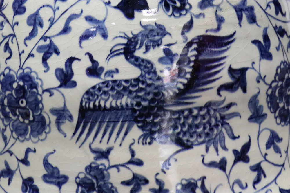 飛行中的鳳凰特寫，羽翼與尾羽以鈷藍繪成，置身纏枝牡丹紋之間