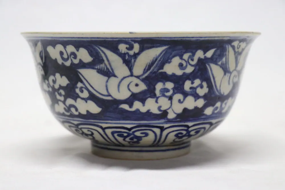 Side view of the bowl showing white doves reserved against a dark cobalt ground of scrolling clouds