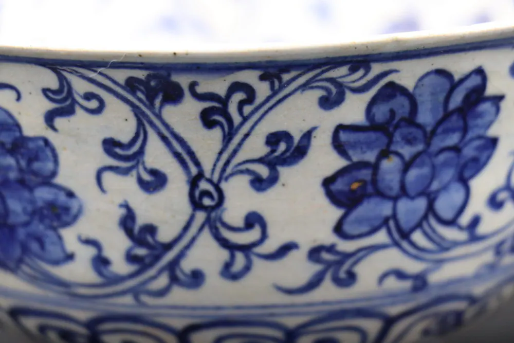 Close-up of the bowl's rim showing lotus blossoms linked by scrolling foliage