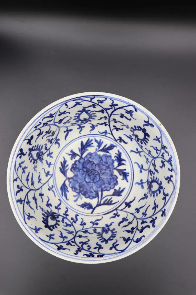 Blue and white bowl viewed from above showing a central peony medallion within a scrolling floral border