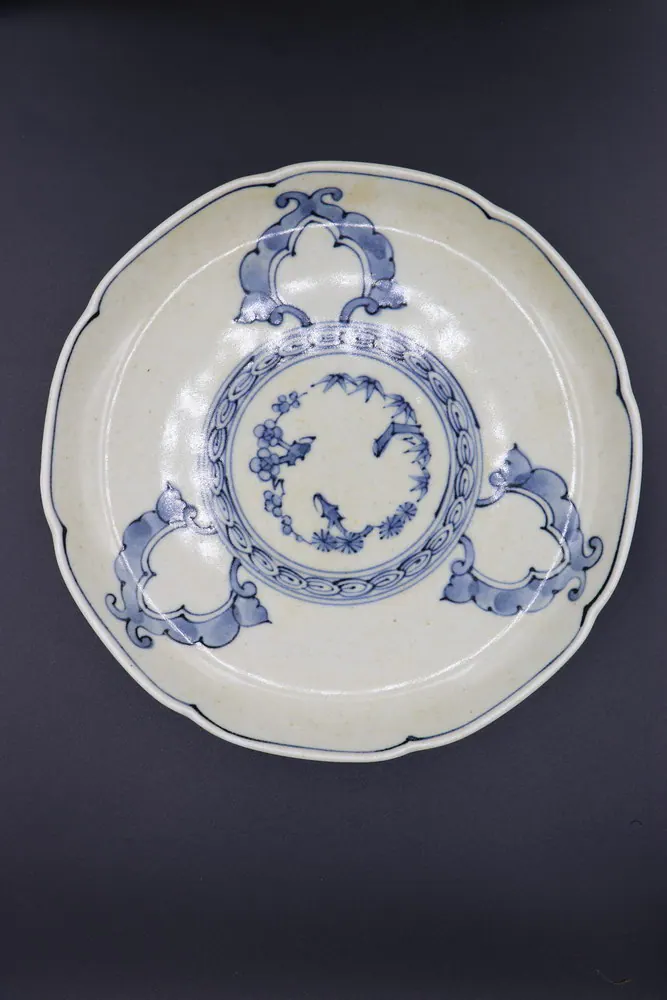Blue and white porcelain plate viewed from above, floral medallion at centre flanked by three ruyi-shaped panels