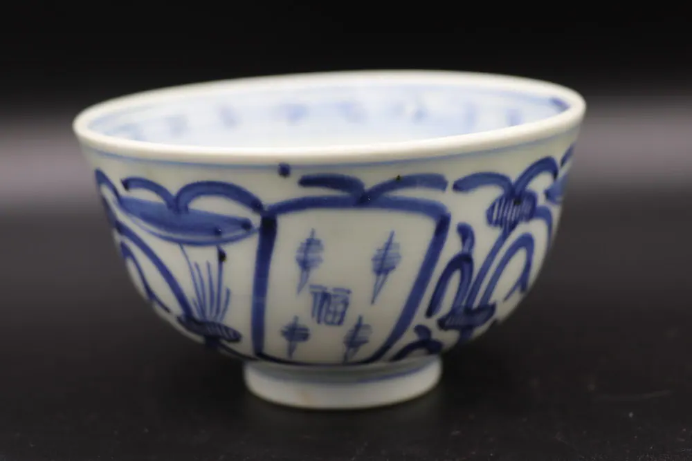 Exterior side view of the bowl showing rectangular panels with small motifs and a looping scroll border