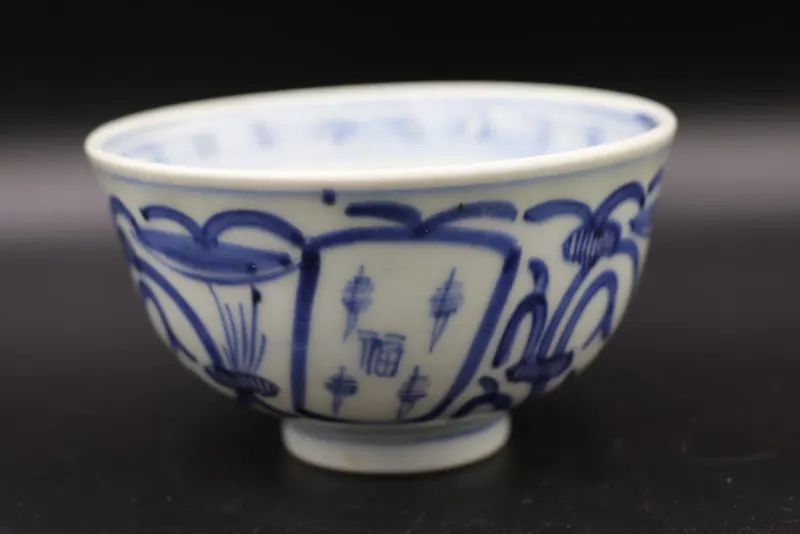 Exterior side view of the bowl showing rectangular panels with small motifs and a looping scroll border
