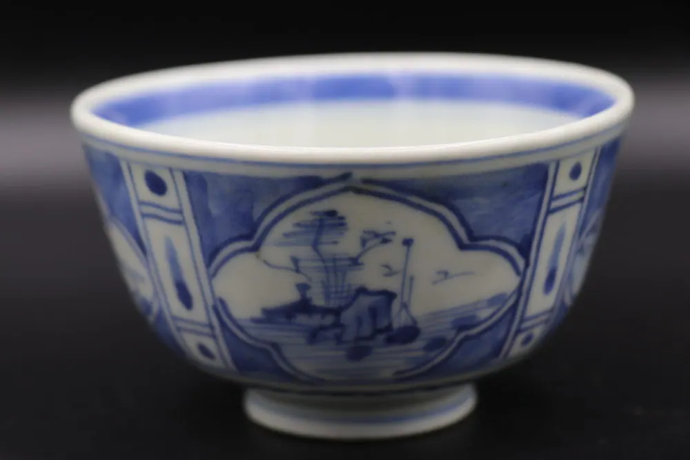 Side view of the blue and white bowl with a lobed landscape cartouche of mountains and a pavilion