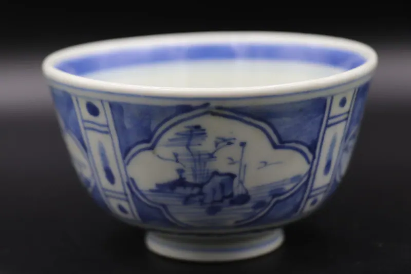 Side view of the blue and white bowl with a lobed landscape cartouche of mountains and a pavilion