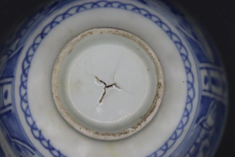 Close-up of the base showing the scalloped lattice border and a star-shaped crack across the foot