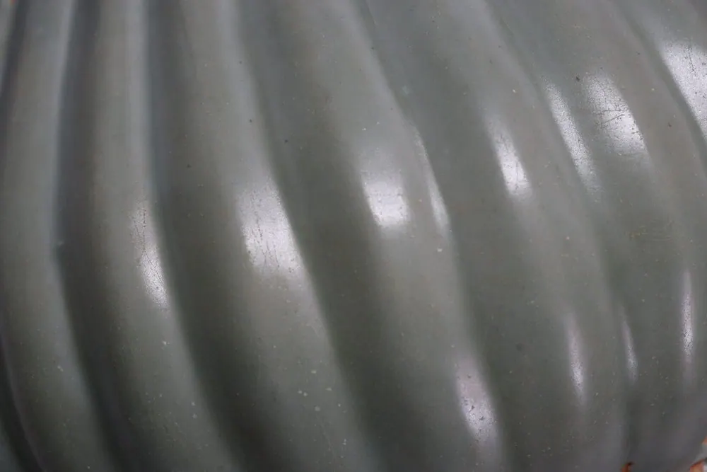 Close-up of the fluted, ribbed surface of the celadon jar's olive green glaze