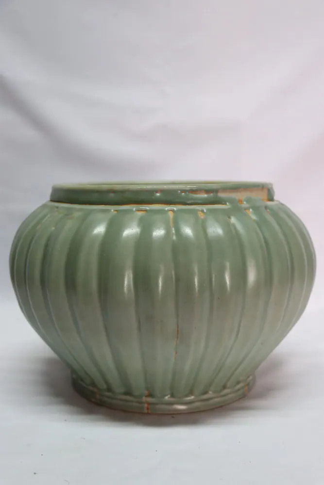 Front view of a celadon jar with a ribbed, melon-lobed body and a short rim, showing firing cracks