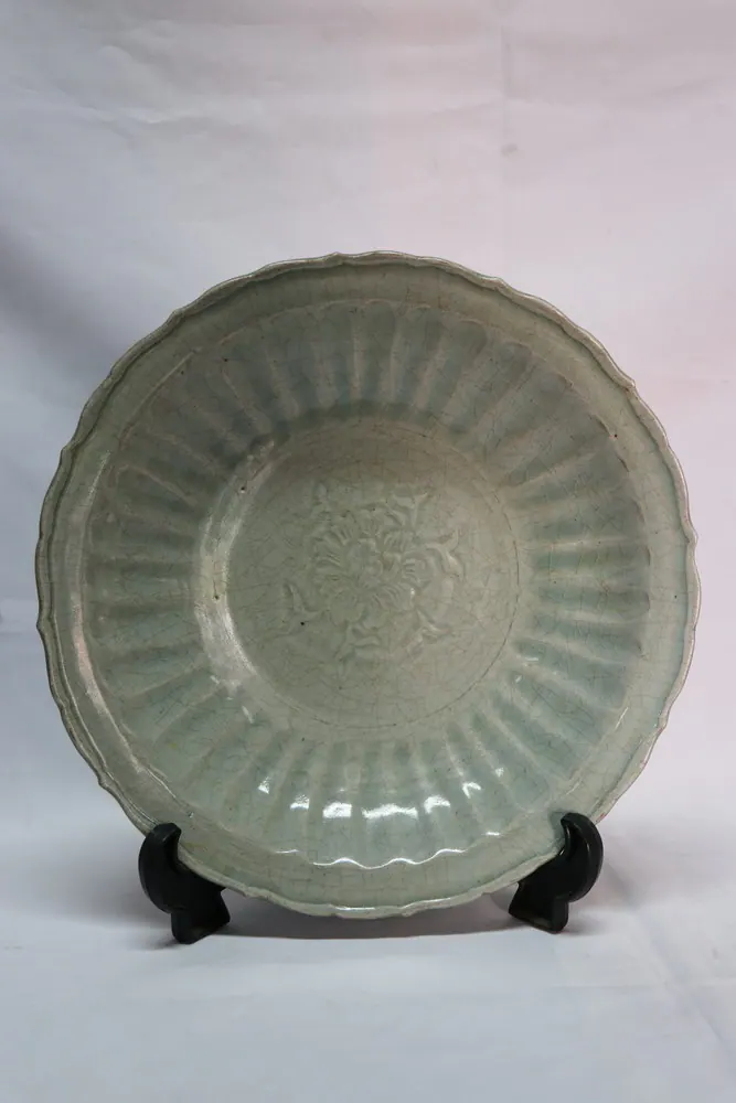 Front view of the celadon plate with a fluted rim and a moulded floral medallion