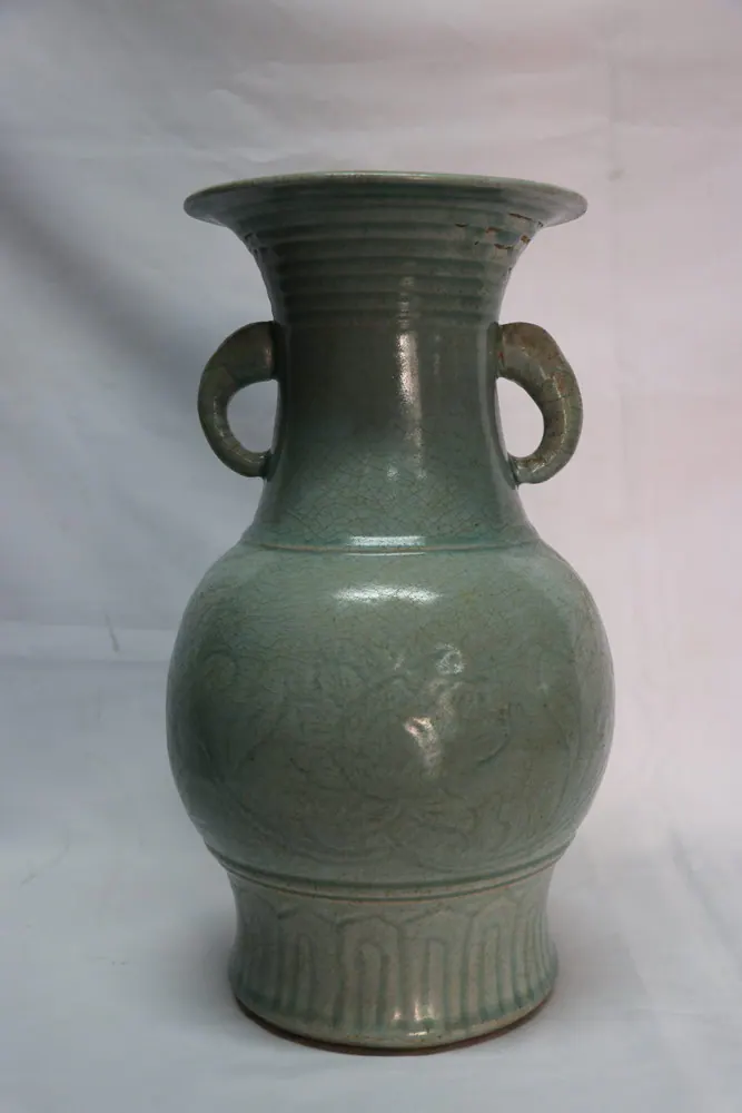 Front view of a celadon vase with two ring handles and a moulded floral body