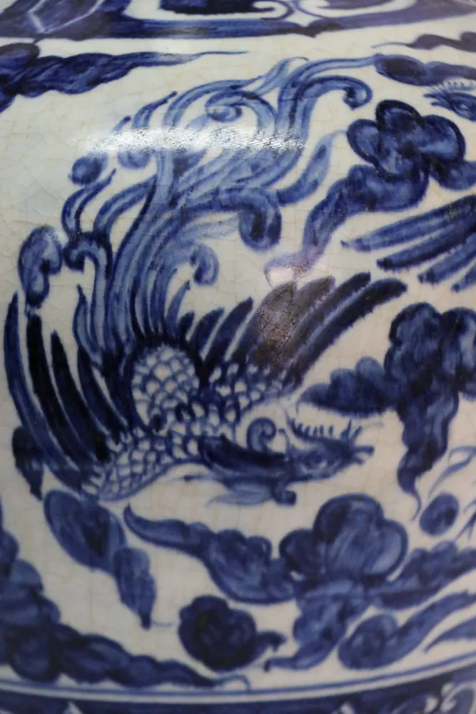 Close-up of a phoenix with finely feathered wings and a crested head amid cloud scrolls