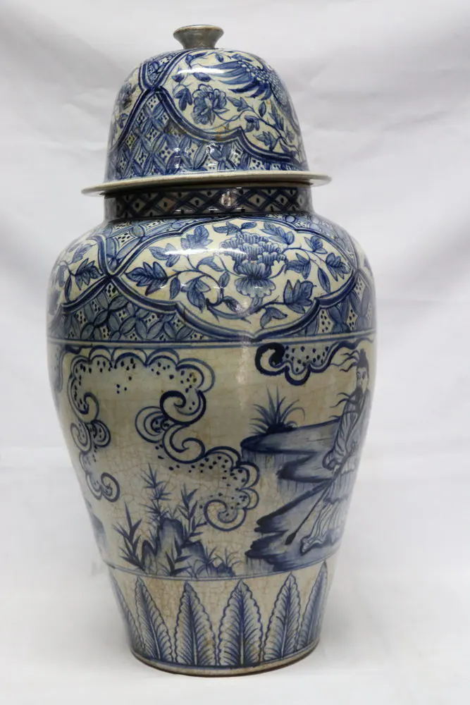 Front view of the covered jar showing a rocky garden landscape beneath the floral-banded shoulder