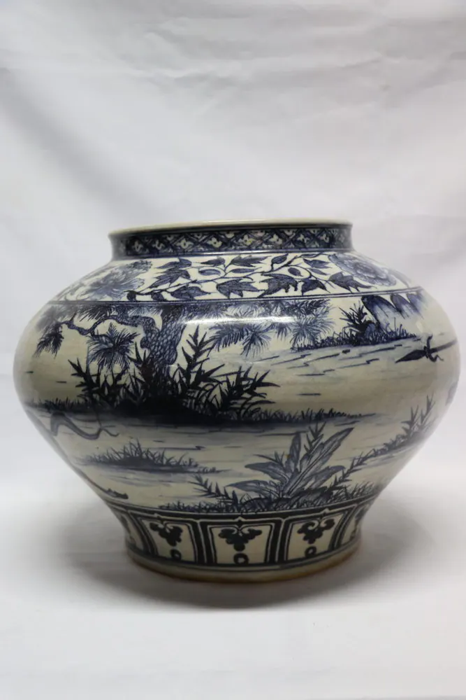 Reverse side of the jar showing a wooded lakeside landscape band above lotus panels at the foot