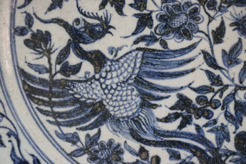 Close-up of a phoenix with feathered crest and wing amid a floral scroll border