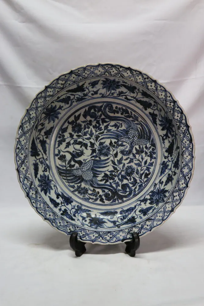 Barbed-rim blue and white charger, front view, with a phoenix pair medallion and diaper-lattice rim border