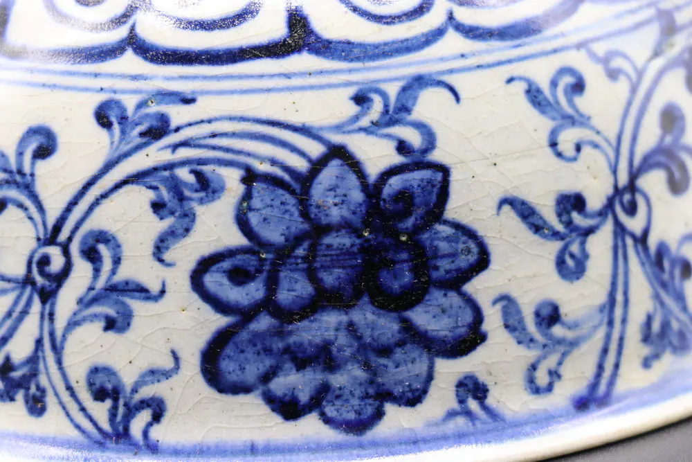 Close-up of a lotus blossom and scrolling leaves beneath the rim's lappet border