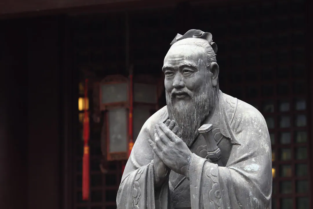 留须圣贤的石像双手合拢，立于悬挂灯笼的寺庙门前