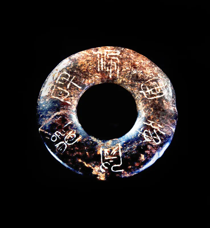 带斑点的褐蓝色石环,中有一孔,环上刻有古文字