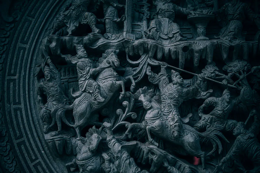 Stone relief of mounted warriors in battle within a key-fret border