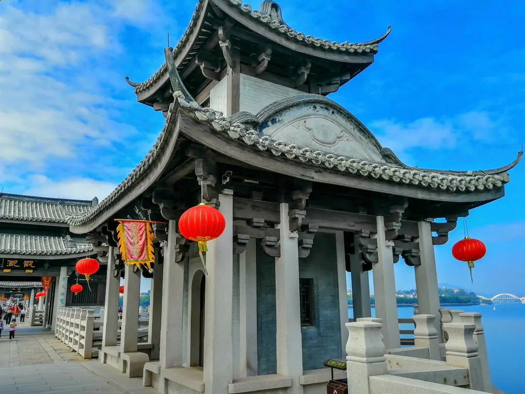 石桥亭阁，飞檐挂红灯笼，旁边是宽阔的河流