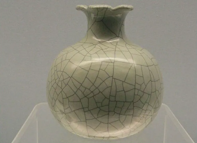 Round jar with a lobed rim under a pale grey-green glaze with bold dark crackle, on a stand
