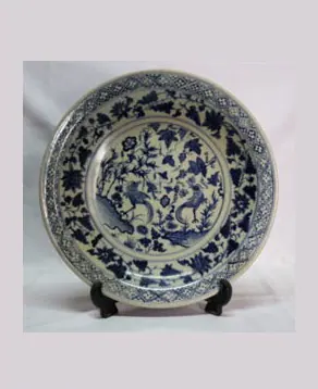 Blue and white charger on a stand, painted with two birds among flowering plants within a diaper rim