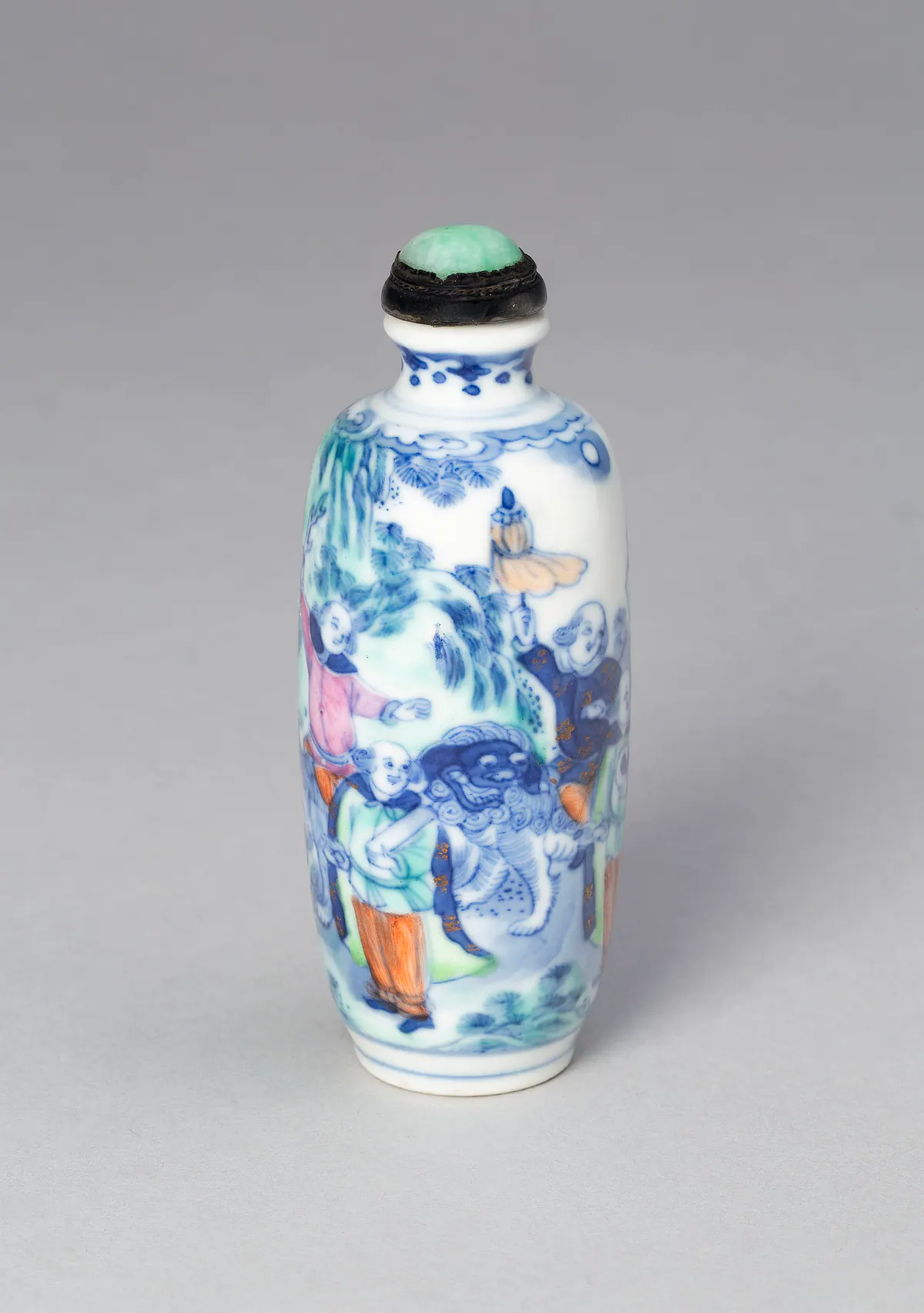 修長瓷鼻煙壺，配綠色石質塞子，以釉下青花與釉上彩繪成，繪身穿長袍的外國人牽著一頭獅子，並撐著傘。