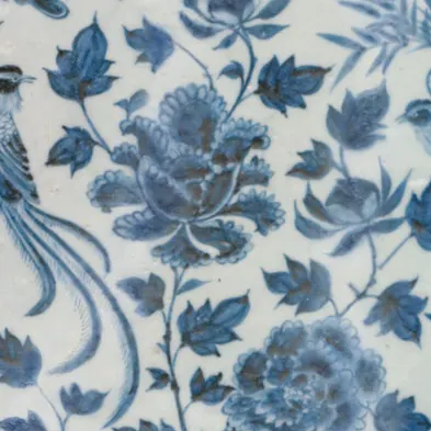 Detail of a Yuan blue and white dish: peony flowers and leaves in deep underglaze cobalt blue, with dark spots where the pigment gathered