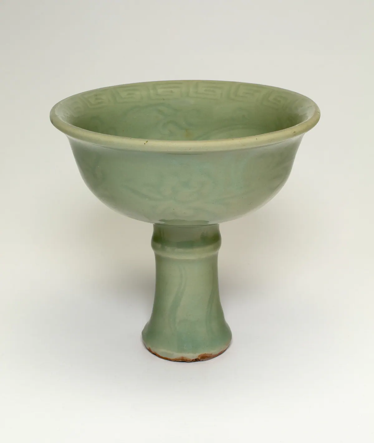 A Yuan Longquan celadon stem cup, a deep rounded bowl with a slightly everted rim on a tall stem with a ridge near the top, with a key-fret band inside the rim and faint moulded scrolls under the green glaze.
