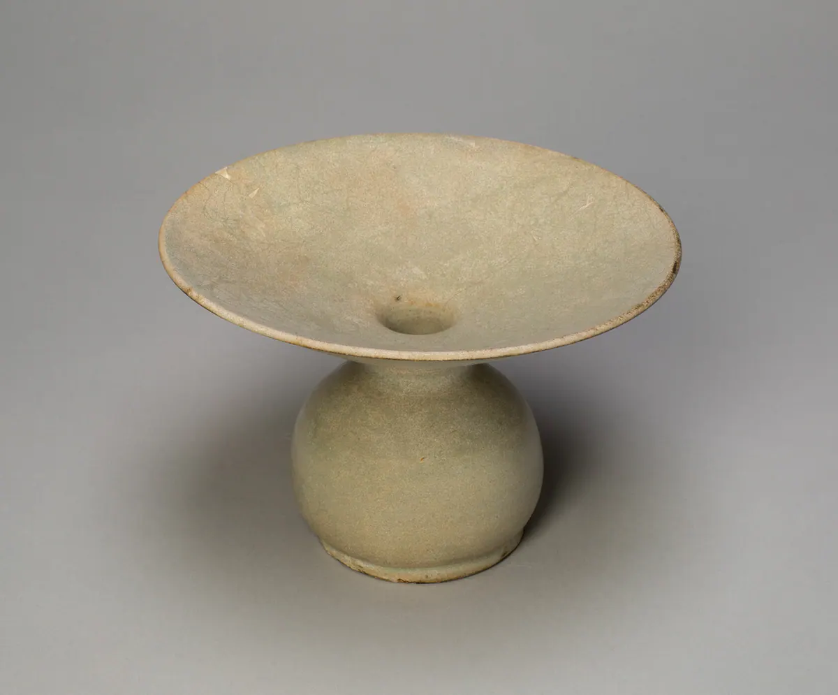 A Yue ware zhadou with a wide, flat dish-shaped mouth above a round body, covered in a pale grey-green crackled glaze.