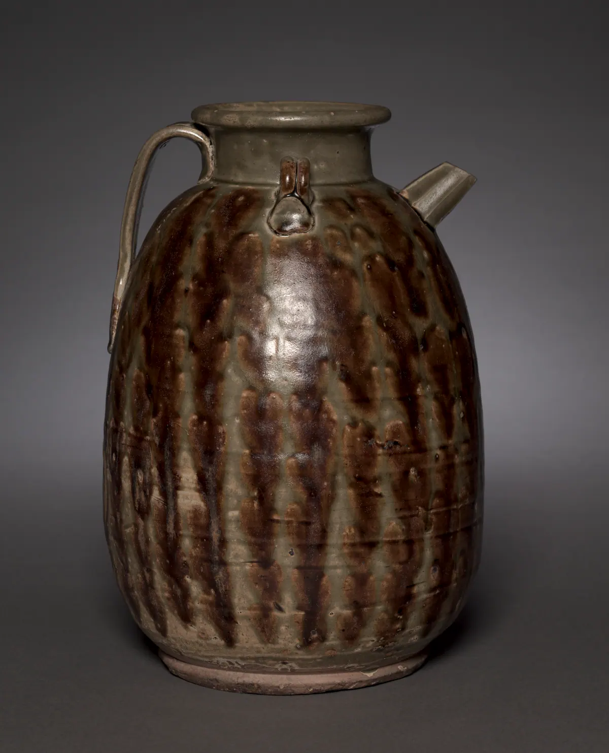 A Changsha ware stoneware ewer with an ovoid body, short spout and strap handle, its olive-green glaze streaked with rows of dark iron-brown splashes.