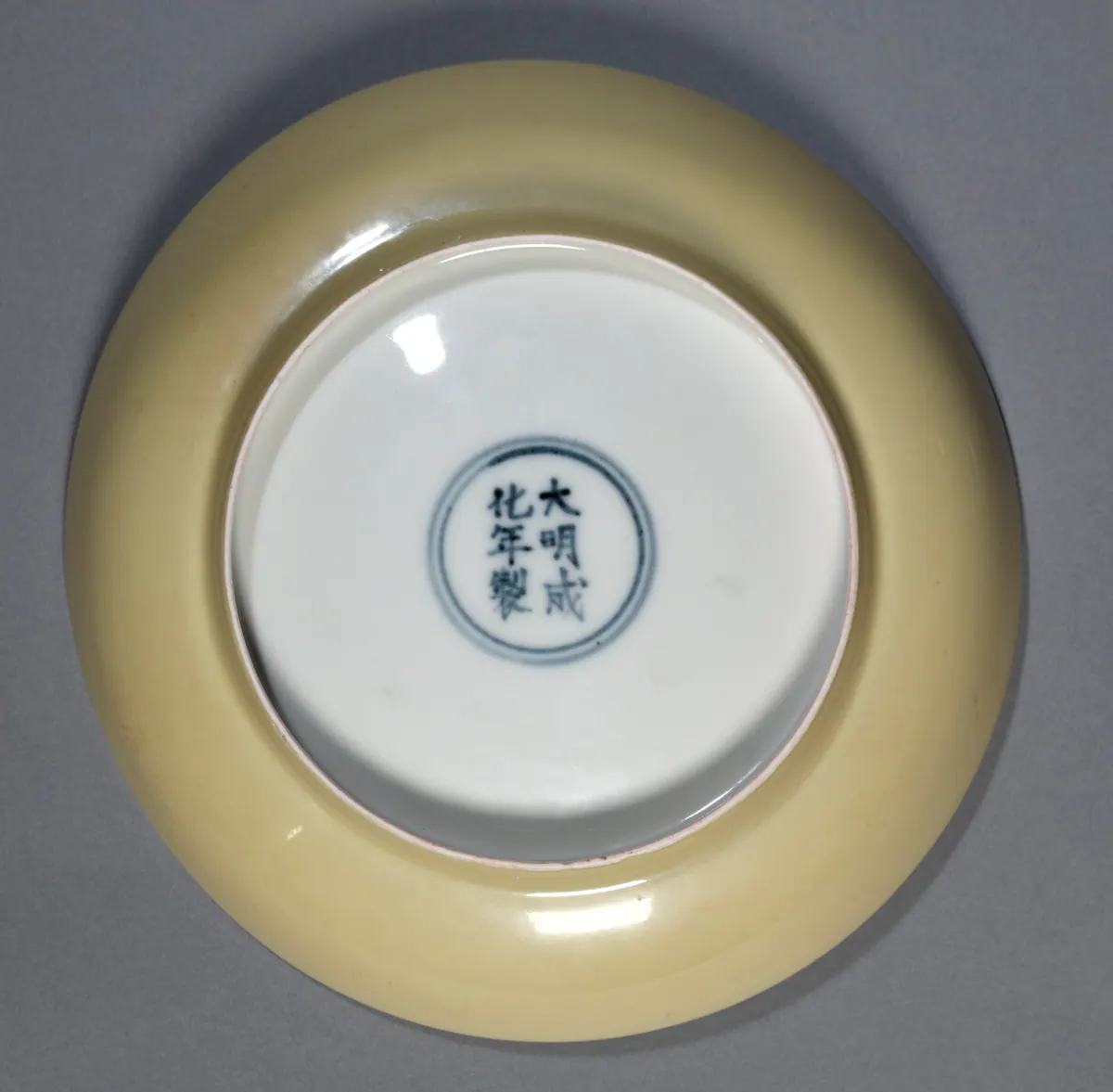 Base of a Chenghua yellow-glazed porcelain dish, with the six-character reign mark Da Ming Chenghua nian zhi written in underglaze blue inside a double circle