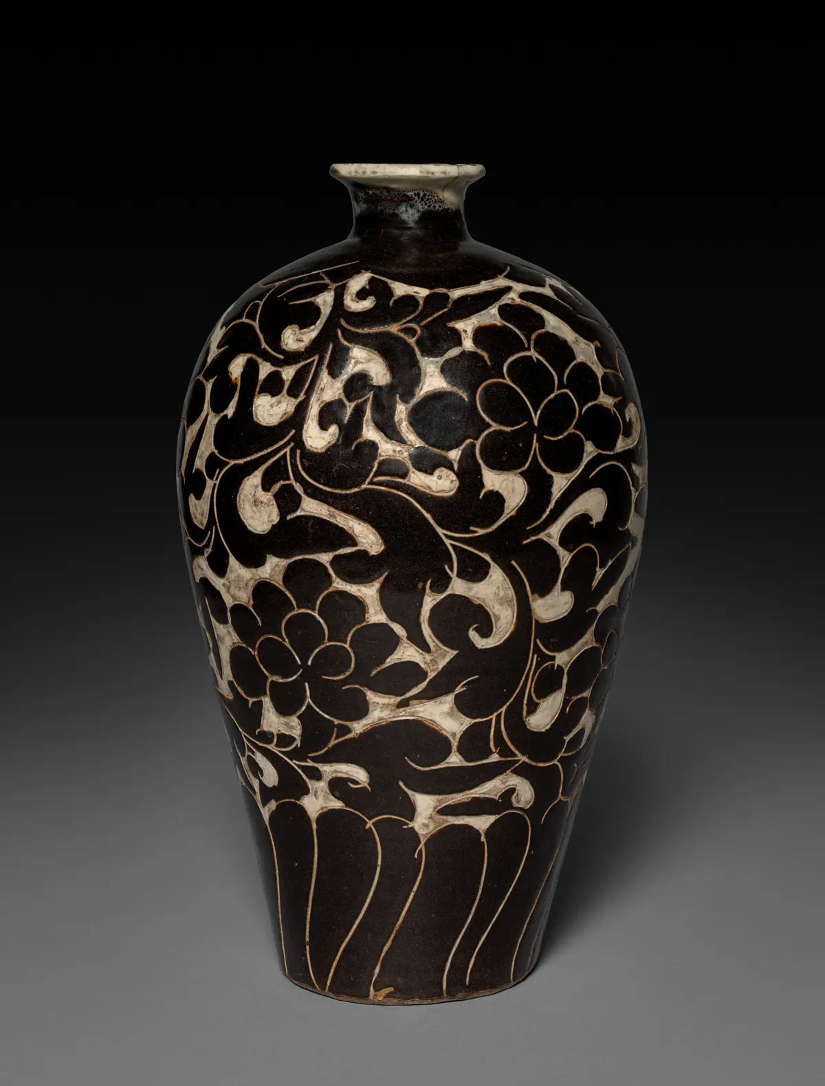 A Cizhou stoneware meiping vase with a small mouth and broad shoulders, decorated with bold peony scrolls standing out dark brown against a pale ground, with long petal shapes towards the base.